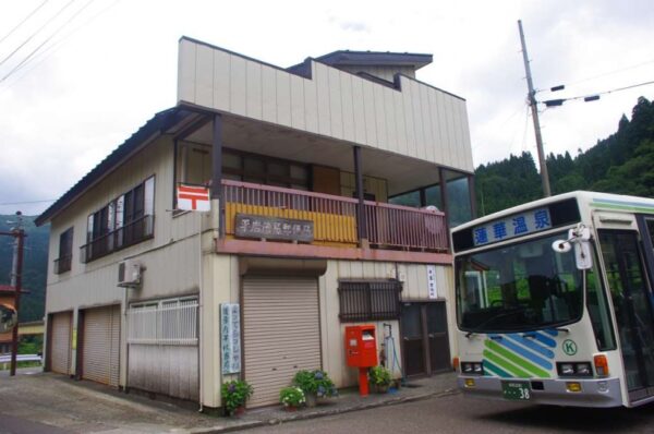 駅前の平岩簡易郵便局と蓮華温泉行きのバス車両
