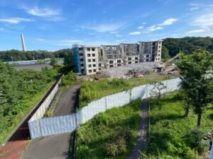解体中の館ヶ丘団地3-12号棟。左背後の館清掃工場（館クリーンセンター）の100m煙突は2021年12月に完成。6月下旬から試運転。10月1日に落成式を行い、本稼働開始予定。